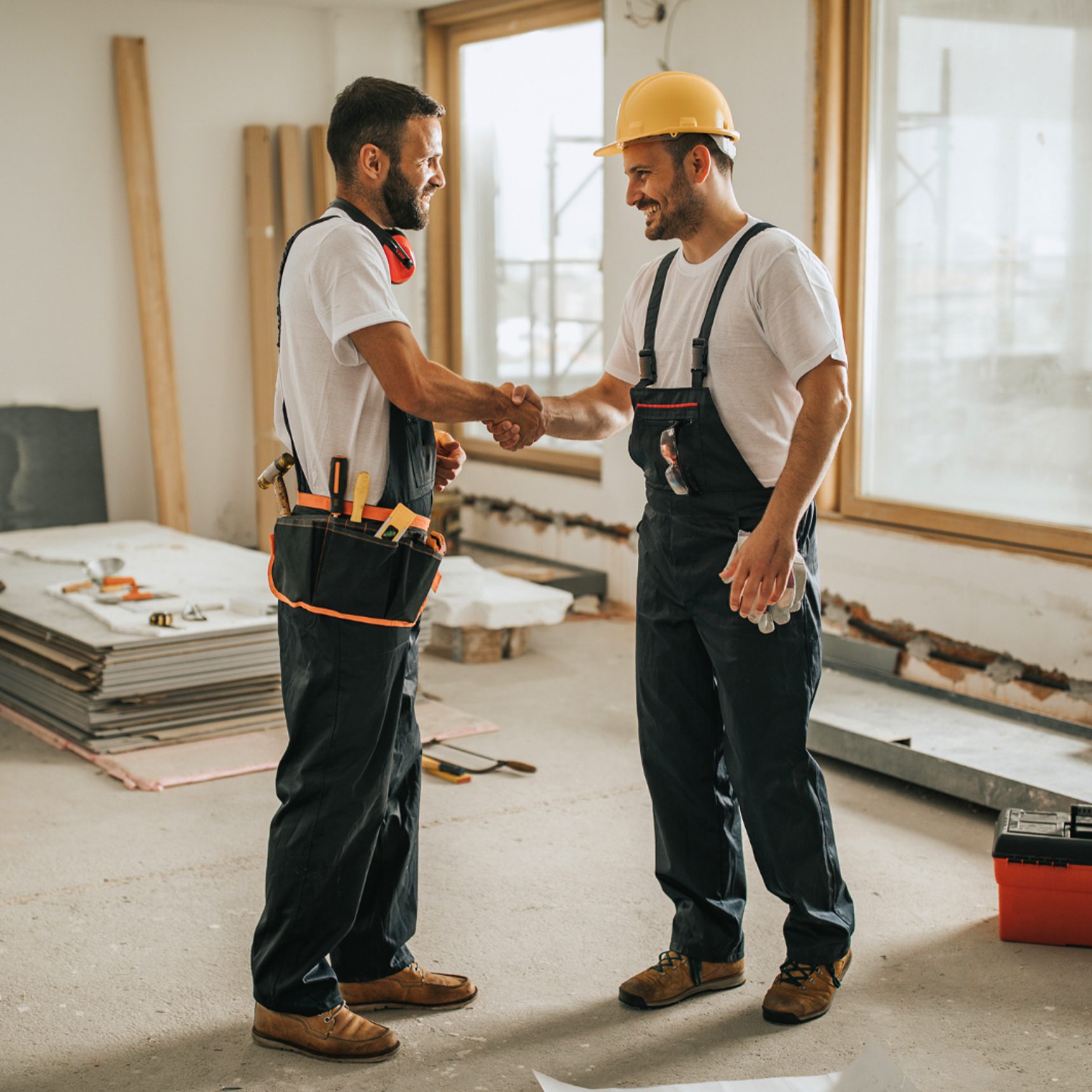 Two workers shake hands in a construction site